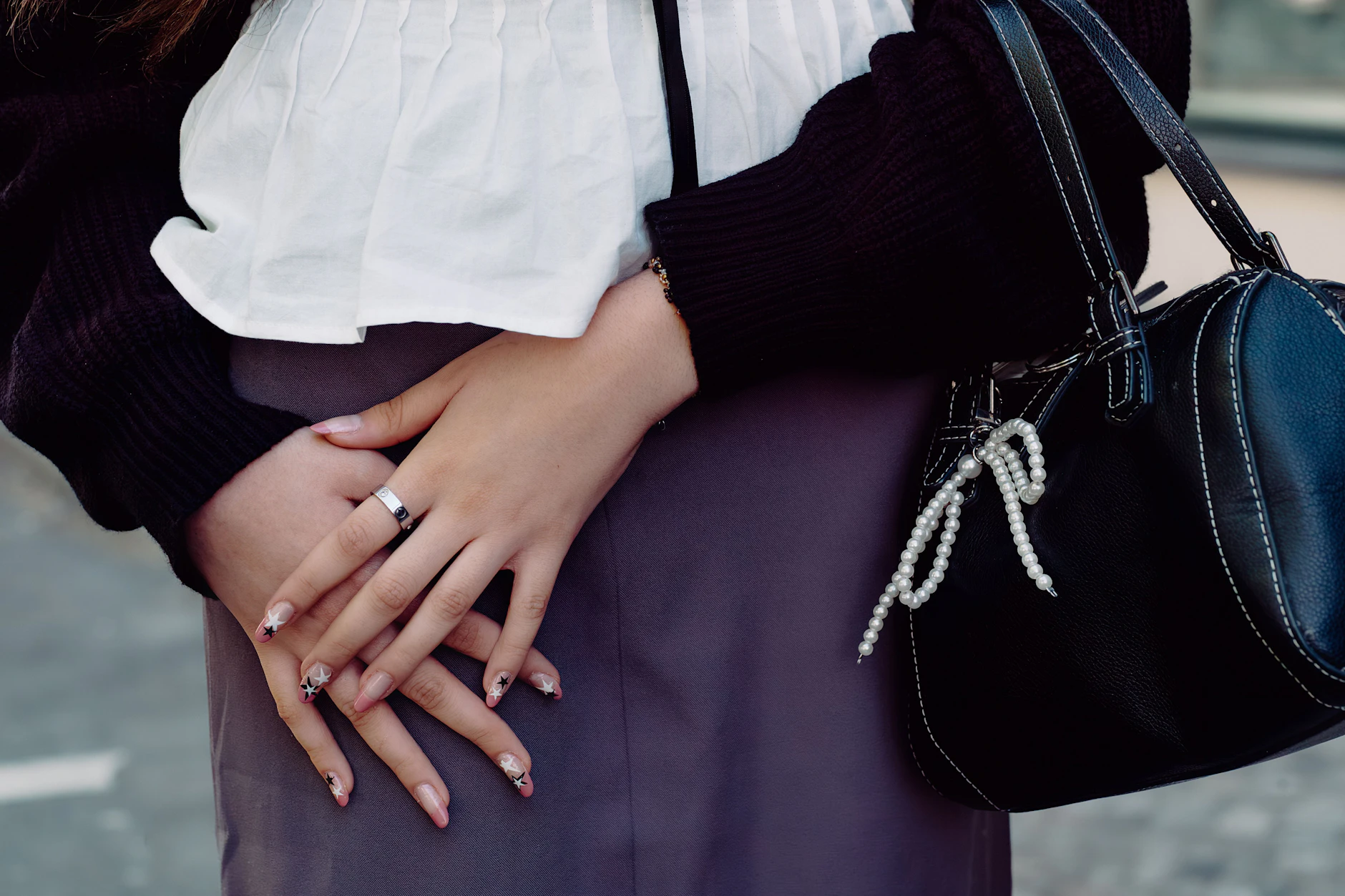 Besonders viel Liebe steckt im Detail: Saras Tasche ziert ein zarter Perlen-Charm, und ihr aufwendiges Nail-Art-Design – ein Mix aus rosa French und schwarz-weißen Sternen – hat sie selbst zu Hause kreiert.