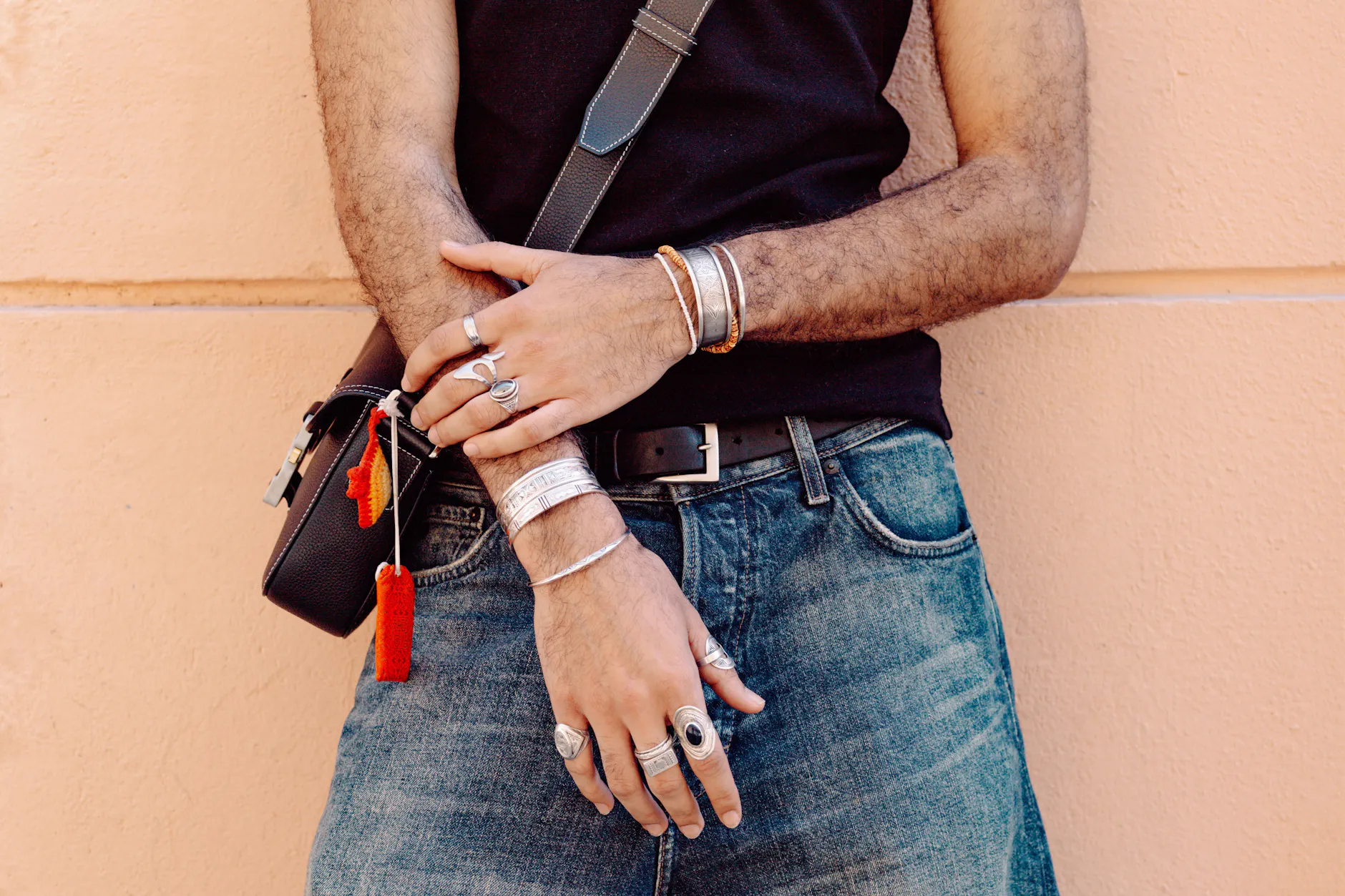 Da gehört jemand stiltechnisch nach Berlin: Robinson kombiniert ein schwarzes Tanktop von der Streetstyle-Brand 44 Label Group mit handgefertigtem Silberschmuck eines nigerianischen Familienfreundes. An seiner Dior-Tasche finden sich persönliche Details wie ein Mitbringsel aus Japan und ein kleines Häkeltier, das er spontan einer älteren Dame in der U-Bahn abgekauft hat.