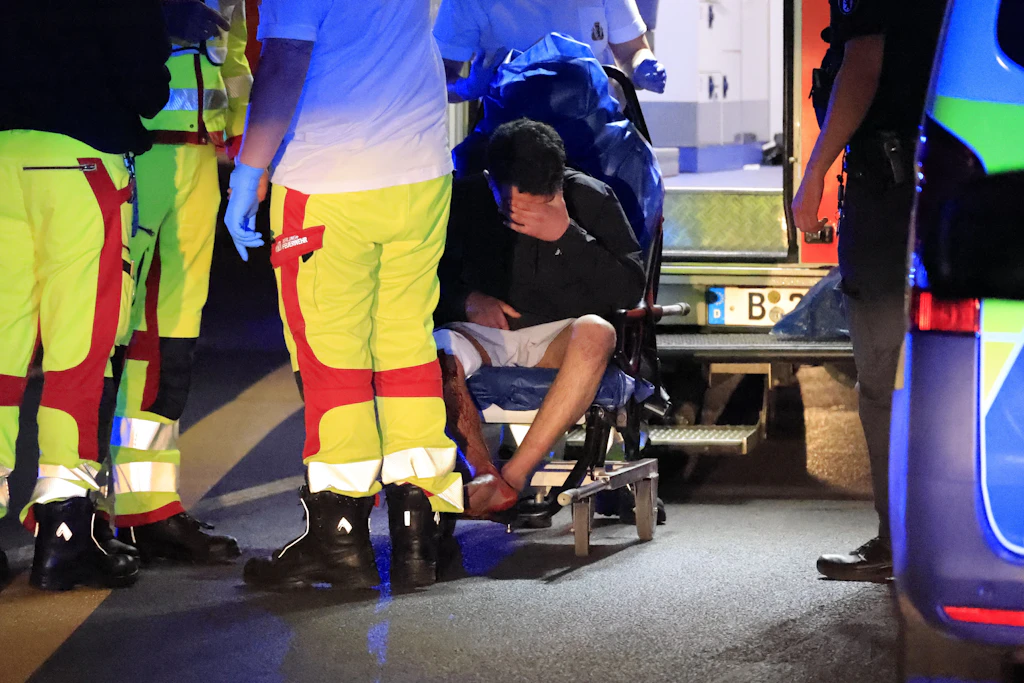 Eine Wunde oberhalb des rechten Knies: Sanitäter transportieren einen der verletzten Männer in ein Krankenhaus.