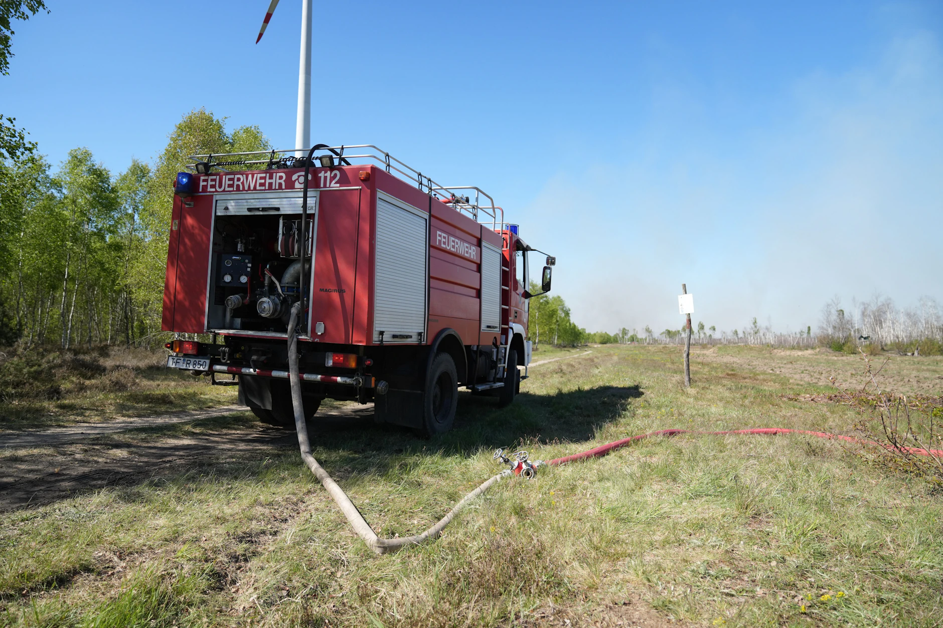 Ein Feuerwehrfahrzeug steht auf einem Weg bei einem Waldgebiet bei Jüterbog. Schneisen und sogenannte Schutzstreifen wie hier sollen das Feuer stoppen.