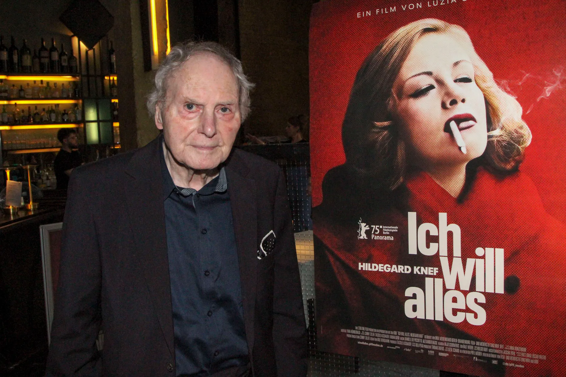 Paul von Schell neben einem Filmplakat, das seine verstorbene Frau Hildegard Knef zeigt.