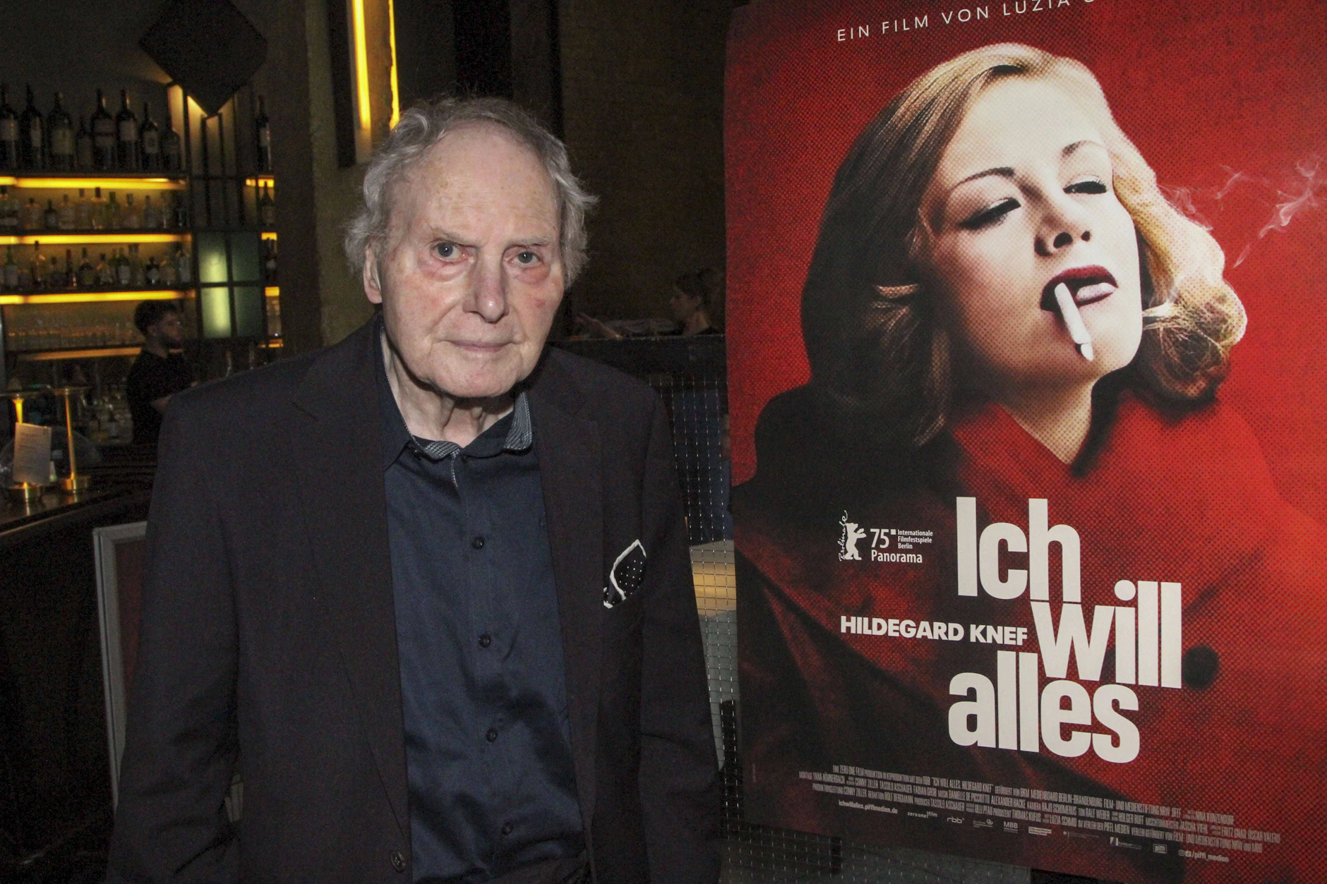Paul von Schell neben einem Filmplakat, das seine verstorbene Frau Hildegard Knef zeigt.