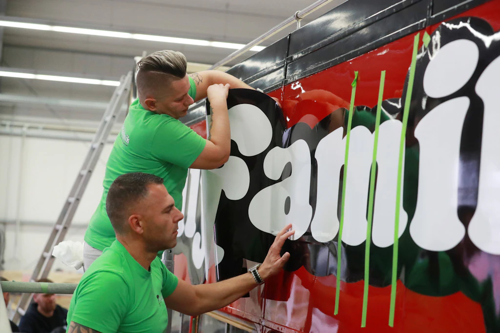 Handarbeit für ein Stück Popgeschichte: Arbeiter bekleben den restaurierten Kelly-Family-Bus mit dem charakteristischen Schriftzug.