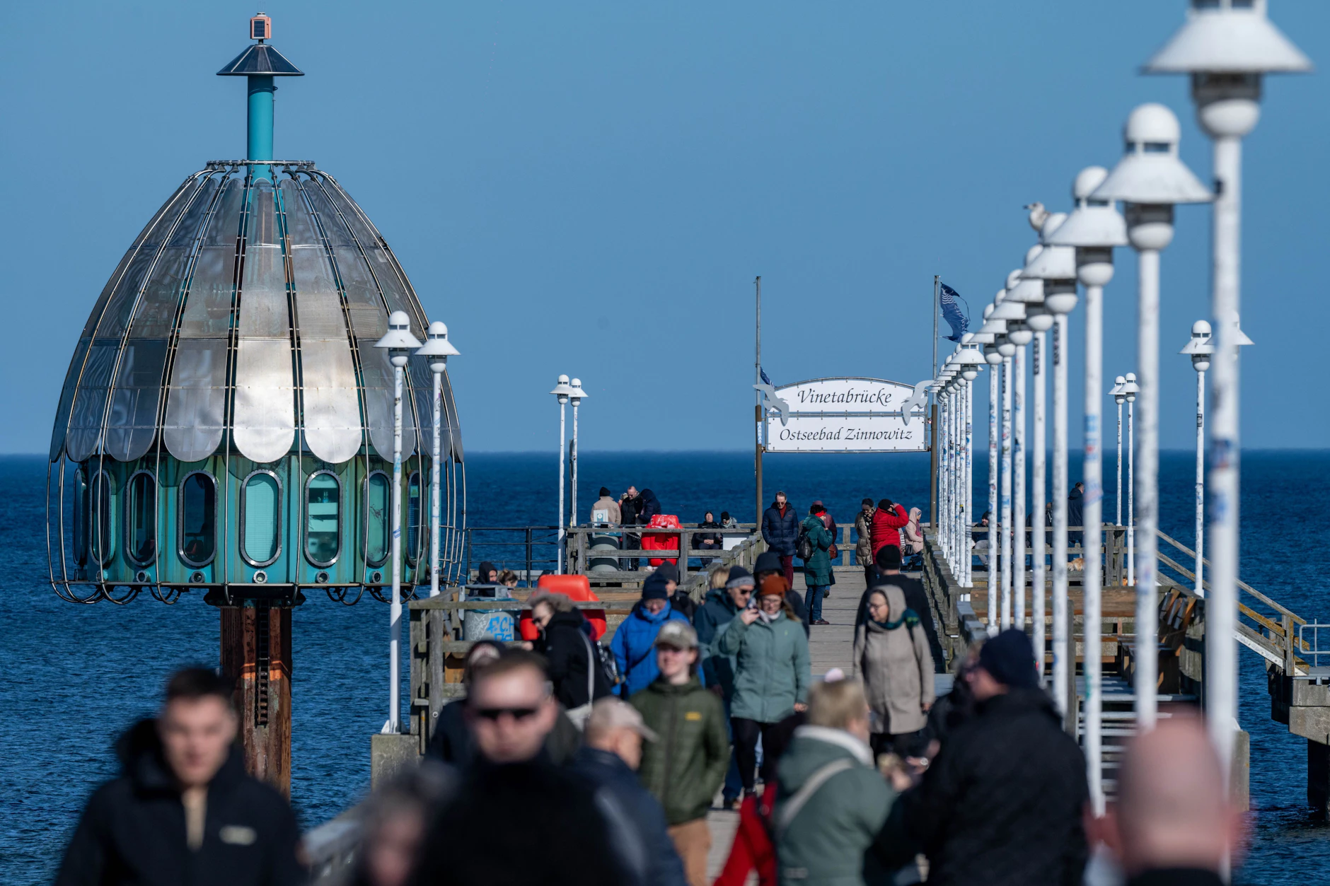 Touristen streben zur bekannten Tauchgondel auf der Seebrücke im Ostseebad Zinnowitz.