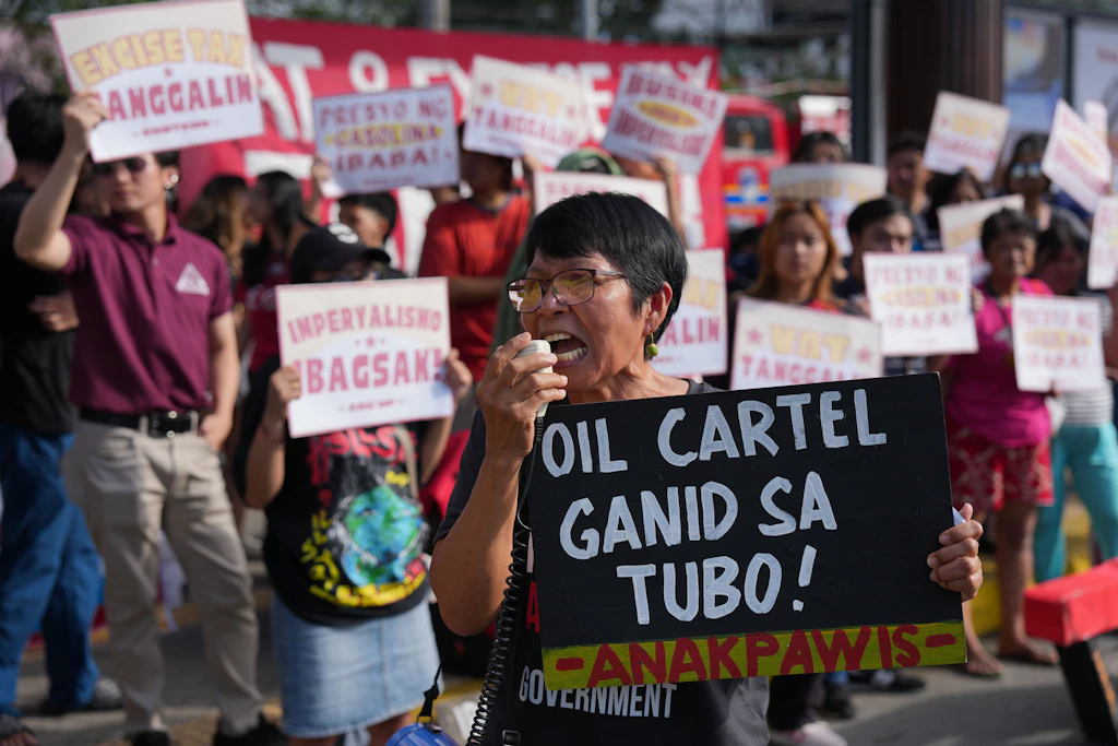Philippinen, Quezon City: Ein Demonstrant hält einen Pappe mit der Aufschrift „Ölkartell, gierig nach Profit“&nbsp;in die Höhe.