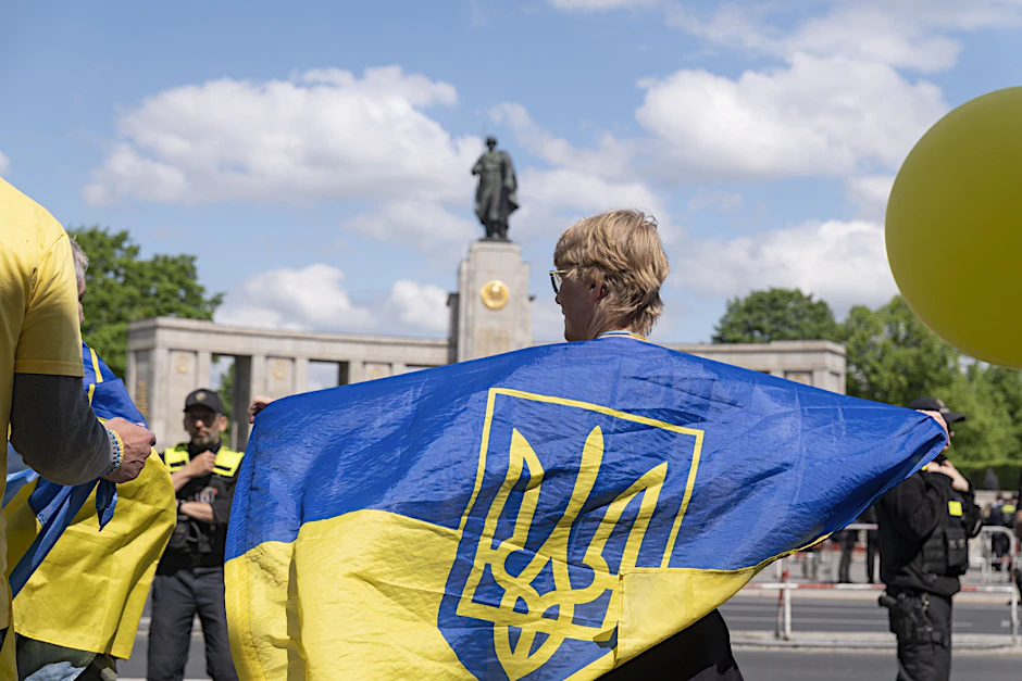 Eine Ukrainerin zeigt Flagge am eingezäunten Sowjetischen Ehrenmal im Tiergarten.