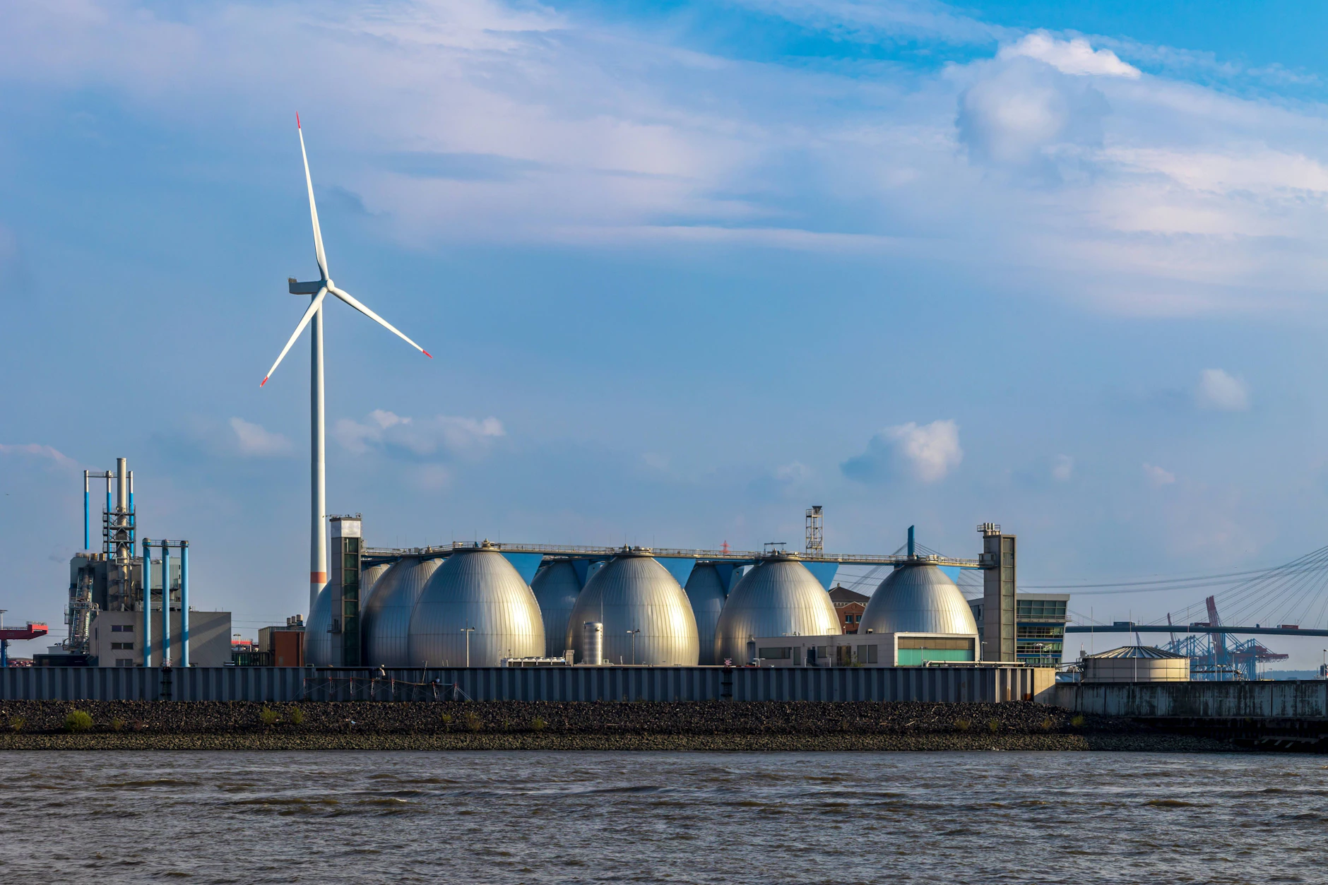 Gas-Silos im Hamburger Hafen vor einer Windkraftanlage.