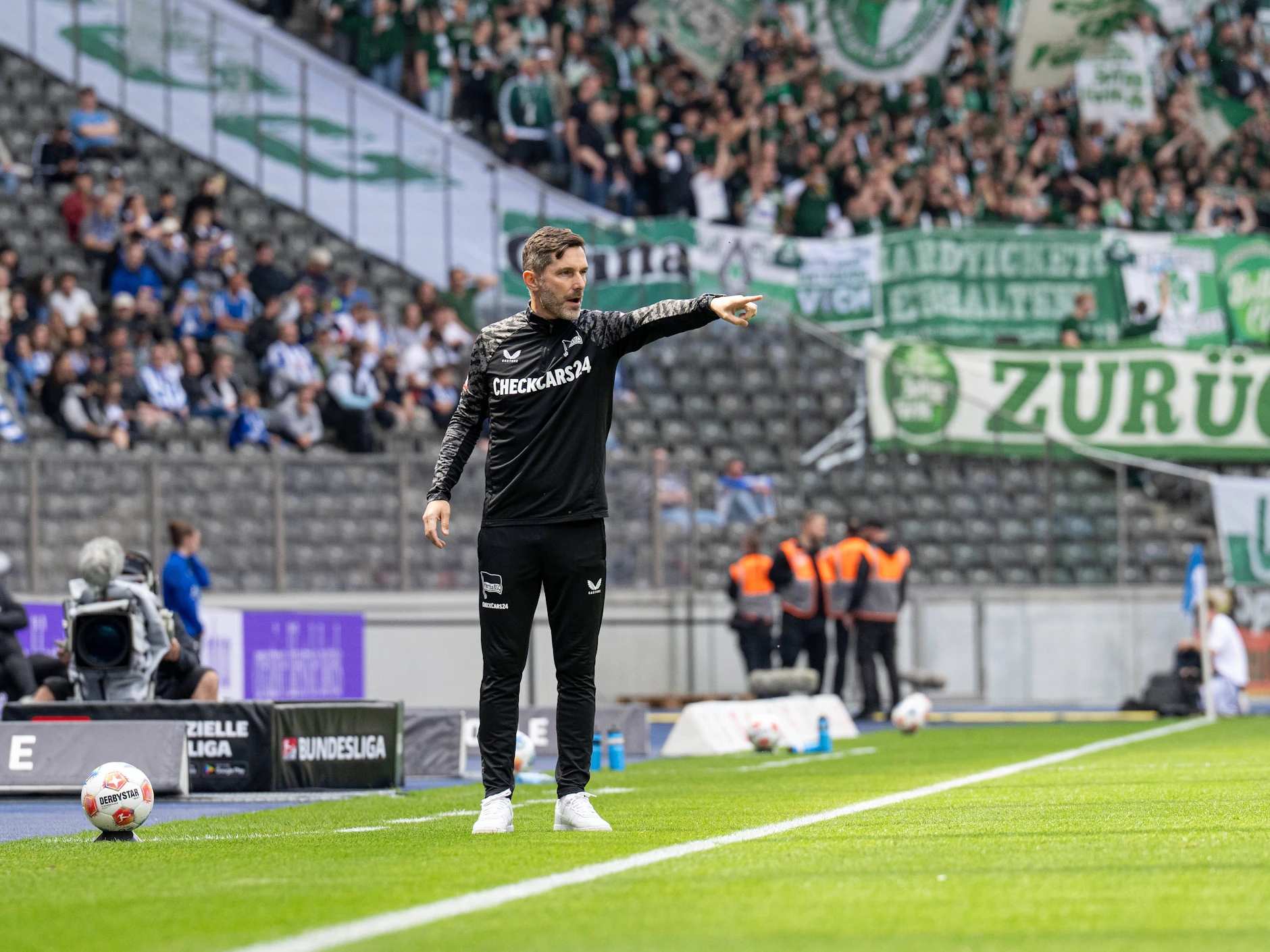 Hertha-Trainer Stefan Leitl an der Seitenlinie. Im Hintergrund sind viele leere Sitzplätze im Olympiastadion.