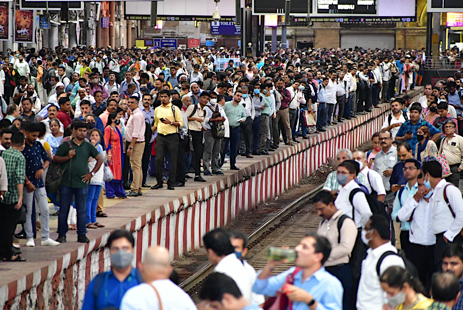 Menschen in Mumbai warten auf die Einfahrt eines Zuges.