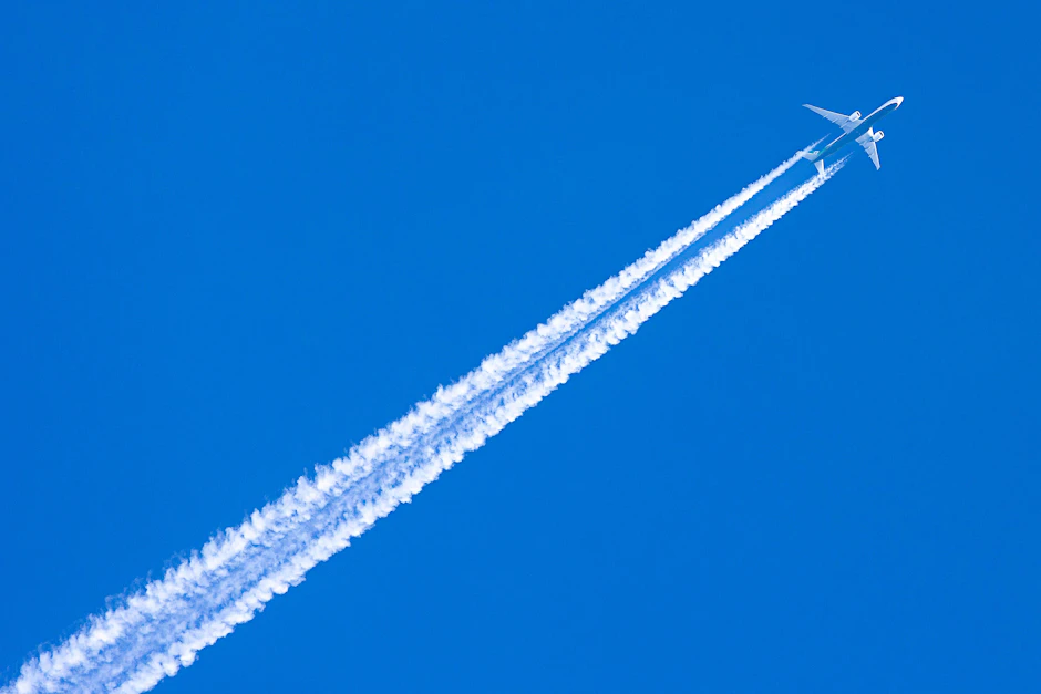 Ein Flugzeug zieht seine Bahnen hoch oben am blauen Himmel. Wenn Maschinen unvorhergesehen umkehren, müssen sie oft tonnenweise Kerosin ablassen, um sicher wieder landen zu können.