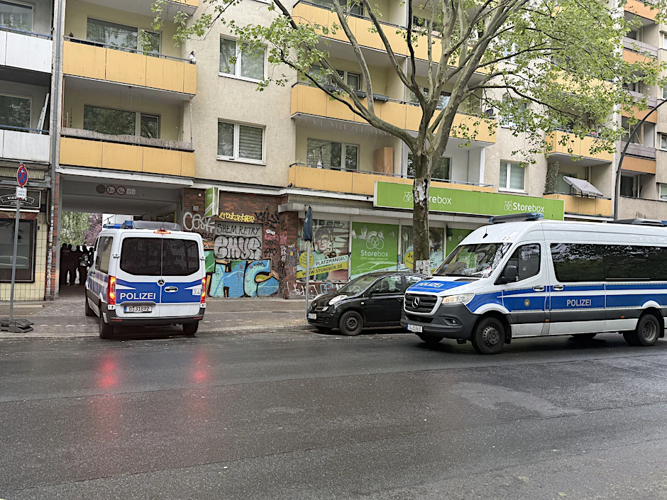 Einsatzfahrzeuge der Polizei stehen bei der Razzia in Kreuzberg vor einem Wohnhaus.