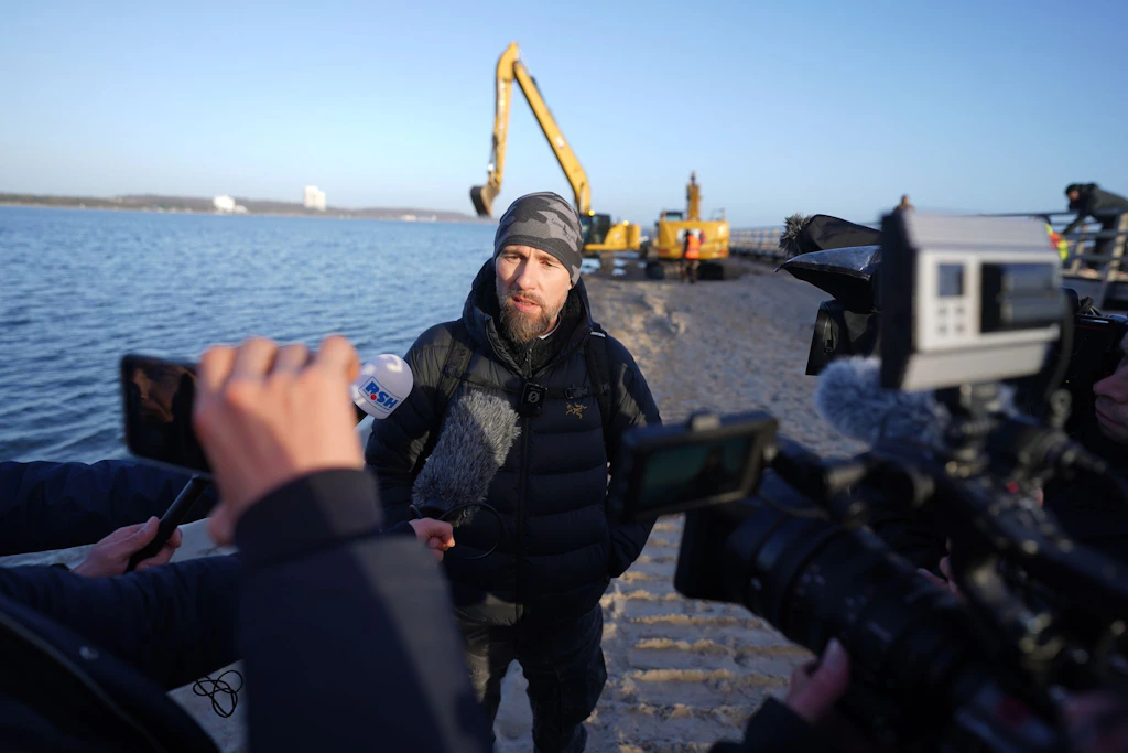 Robert Marc Lehmann, Meeresbiologe, spricht mit den Medien am Strand, wo in der Nähe der gestrandete Buckelwal im Wasser gelegen hatte.