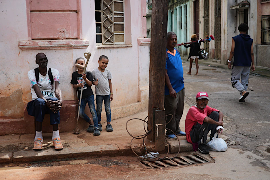 17.03.2026, Kuba, Havanna: Menschen sitzen während eines Stromausfalls in Havanna auf dem Bürgersteig.