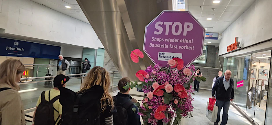 Im Bahnhof Friedrichstraße sind lauter Blumensträuße und Stoppschilder aufgetaucht. Beim genauen Hinsehen klärt sich auf, was dahintersteckt.