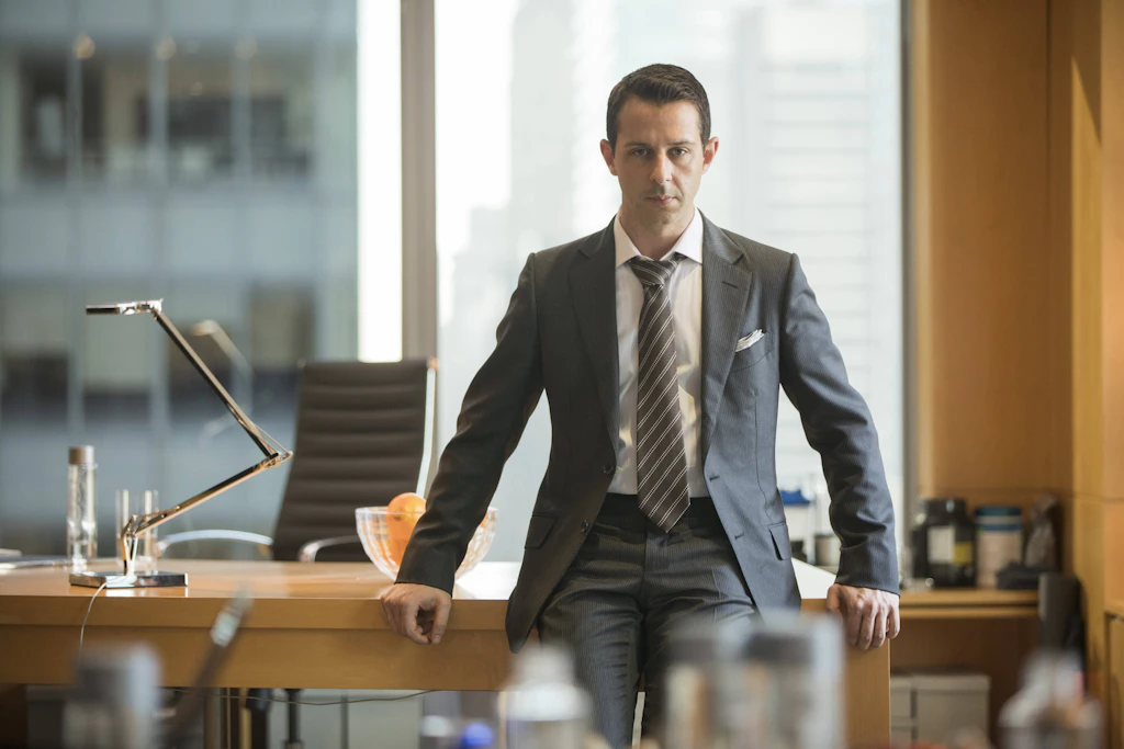Das Paradebeispiel für „Business Formal“: In der Welt der Hochfinanz- und Chefetagen, wie hier in „Succession“, sind der perfekt abgestimmte dunkle Anzug und die Krawatte die eiserne Regel – die Büros haben hoffentlich Klimaanlage.