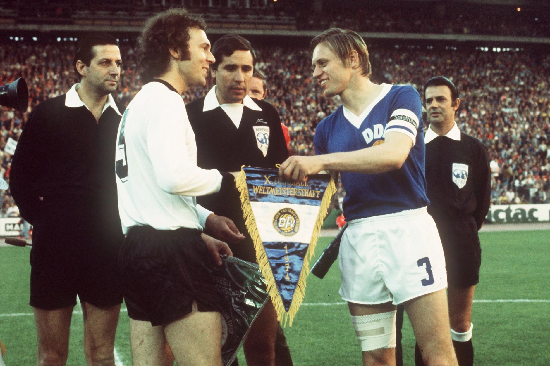 Eines der legendärsten Fotos der Fußball-Geschichte: Franz Beckenbauer und DDR-Kapitän Bernd Bransch tauschen die Wimpel vor dem Duell in Hamburg bei der WM 1974.