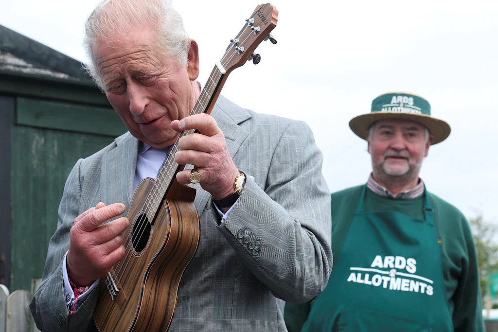 König Charles III. (l) spielt während seines Besuches in Nordirland auch eine Ukulele.