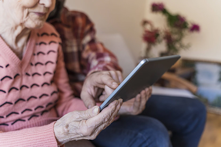 Ein Mann zeigt der Oma etwas auf dem Tablet: Ob sie zusammen nach der NSDAP-Vergangenheit der Familie suchen?