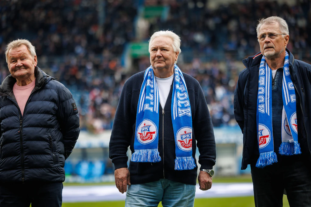 Gerd Kische (M.) brachte Ende April 2026 die 76er-Goldmannschaft nach Rostock. Links: Konrad Weise, rechts Lothar Kurbjuweit. Sie spielten auch zusammen die 74er-WM in der Bundesrepublik.