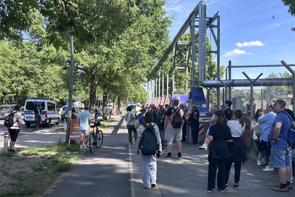 Besucher, die das Feld verlassen mussten, warten vor den Eingängen (hier Columbiadamm), während vermummte SEK-Beamte in mehreren zivilen Transportern das Gelände befahren.