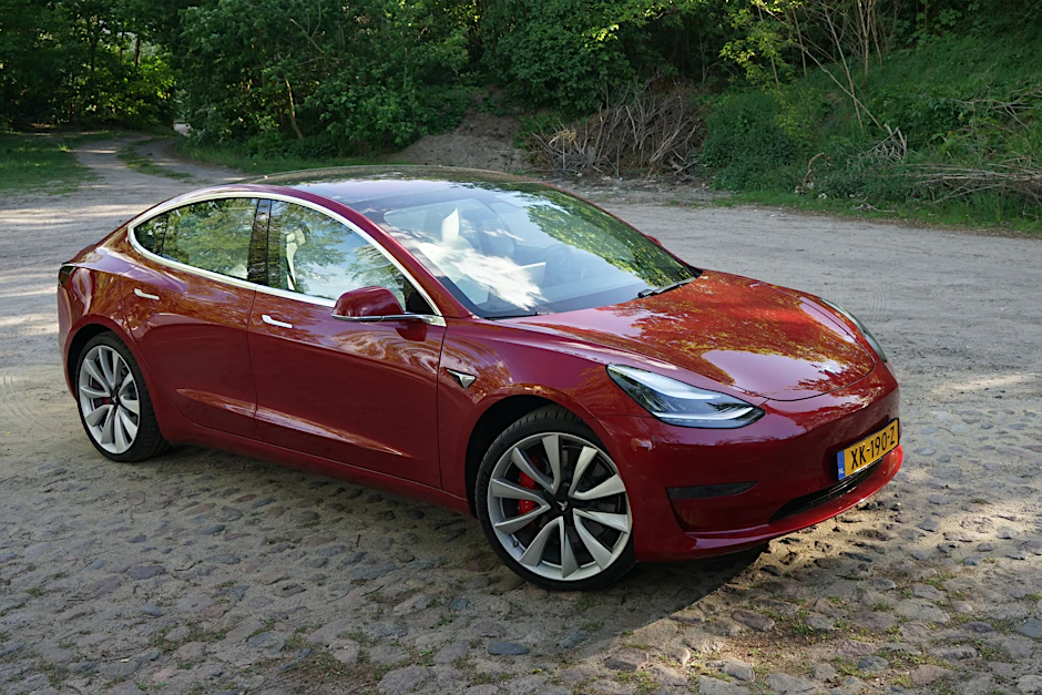 Tesla Model 3 in Rot auf Kopfsteinpflaster: Platz 1 im Preis-Reichweiten-Ranking.