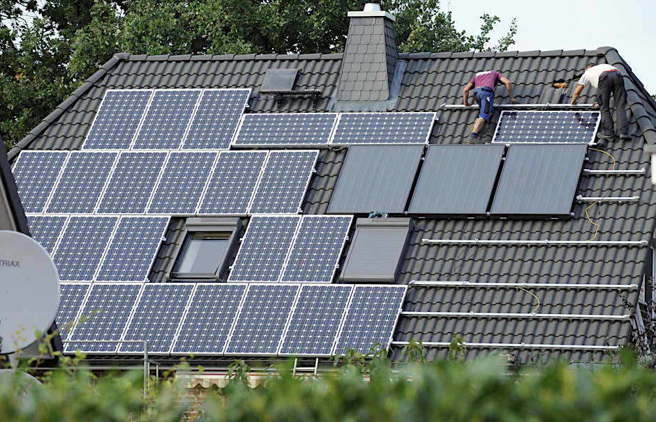 Auf einem Einfamilienhaus wird eine Photovoltaikanlage installiert.