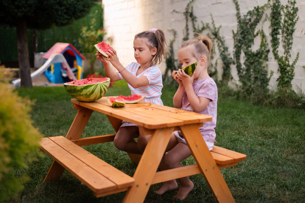 Zwei Mädchen genießen in freier Natur eine Wassermelone. In der Hauptstadt laden viele Parks Familien ein, gemeinsam das Wetter und die Natur zu genießen und zu entdecken.