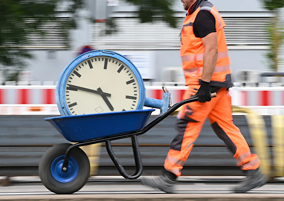 Ein Arbeiter transportiert eine Bahnhofsuhr auf einer Schubkarre.