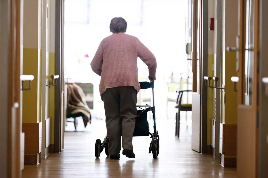 Eine Seniorin geht am Rollator über den Flur eines Pflegeheims: Die Pflegeversicherung verzeichnet ein Millionen-Defizit im ersten Halbjahr 2026.