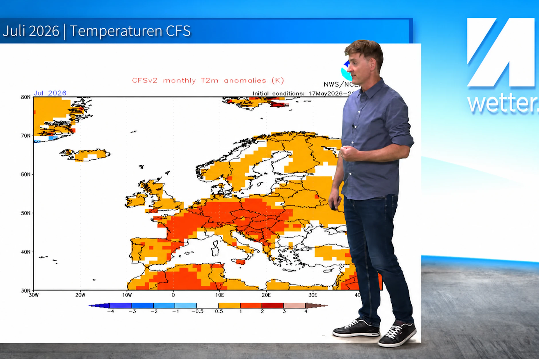 Meteorologe Dominik Jung steht vor einer Wetterkarte des amerikanischen Wettermodells, die flächendeckend für Juli in ganz Europa zu warme Temperaturen anzeigt.