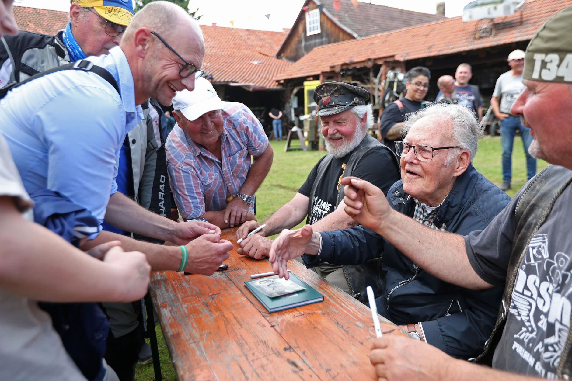 Radsportlegende „Täve“ Schur (2.v.r.) schreibt auf dem Harzer Bikeschmiede-Festival Autogramme.