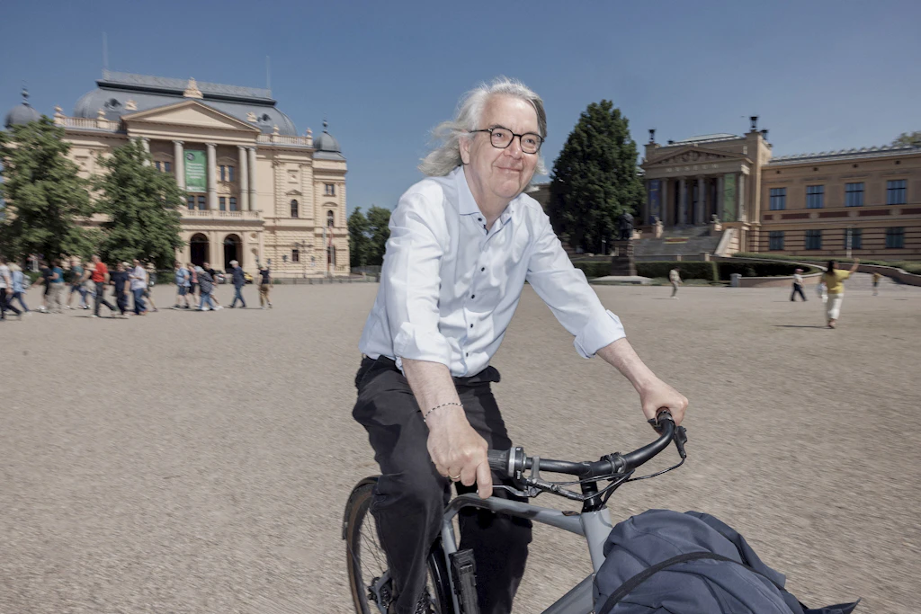 Generalintendant und Geschäftsführer Hans-Georg Wegner fährt auf dem Fahrrad über den Platz vor dem Schweriner Staatstheater&nbsp; zur Ausweichspielstätte im Theaterzelt im Küchengarten.