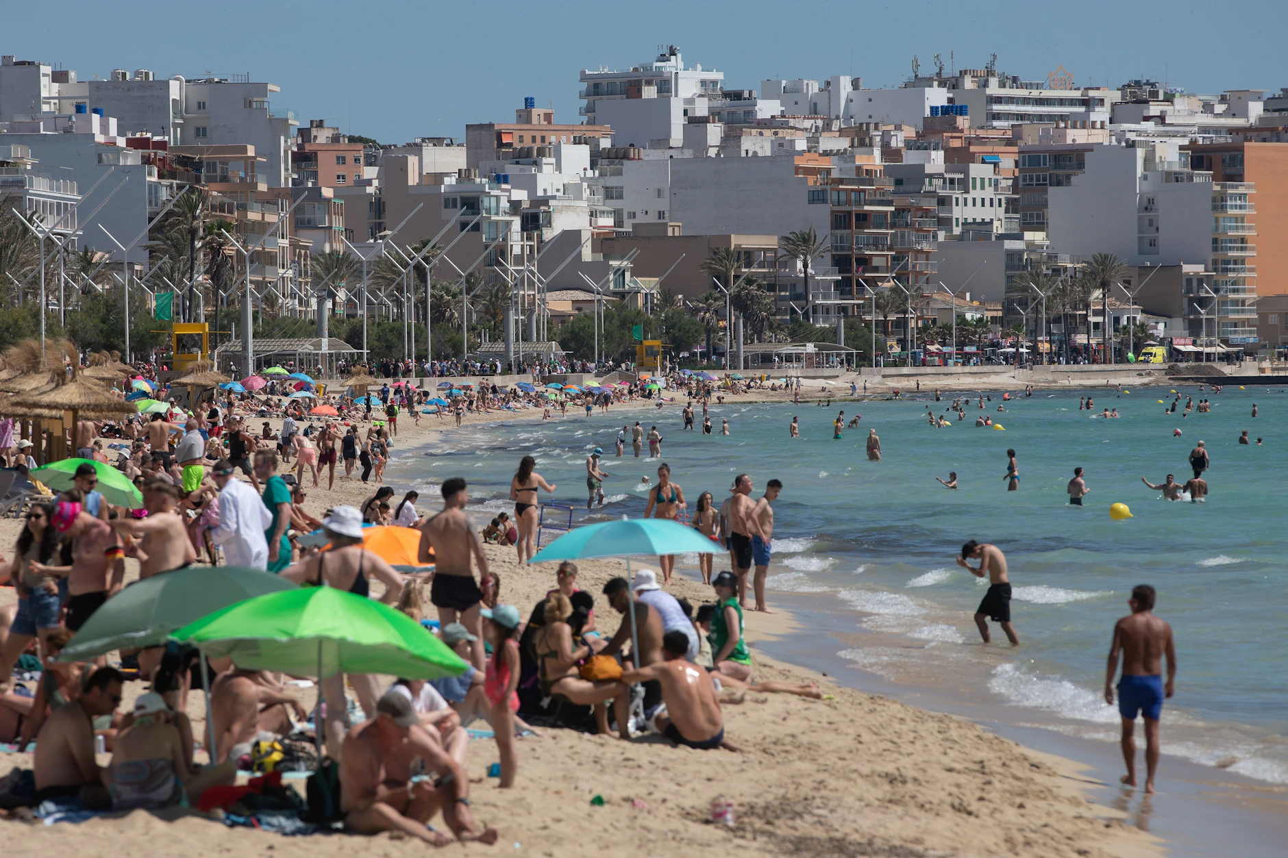 Menschen sonnen sich und schwimmen an der Playa de Palma auf Mallorca.