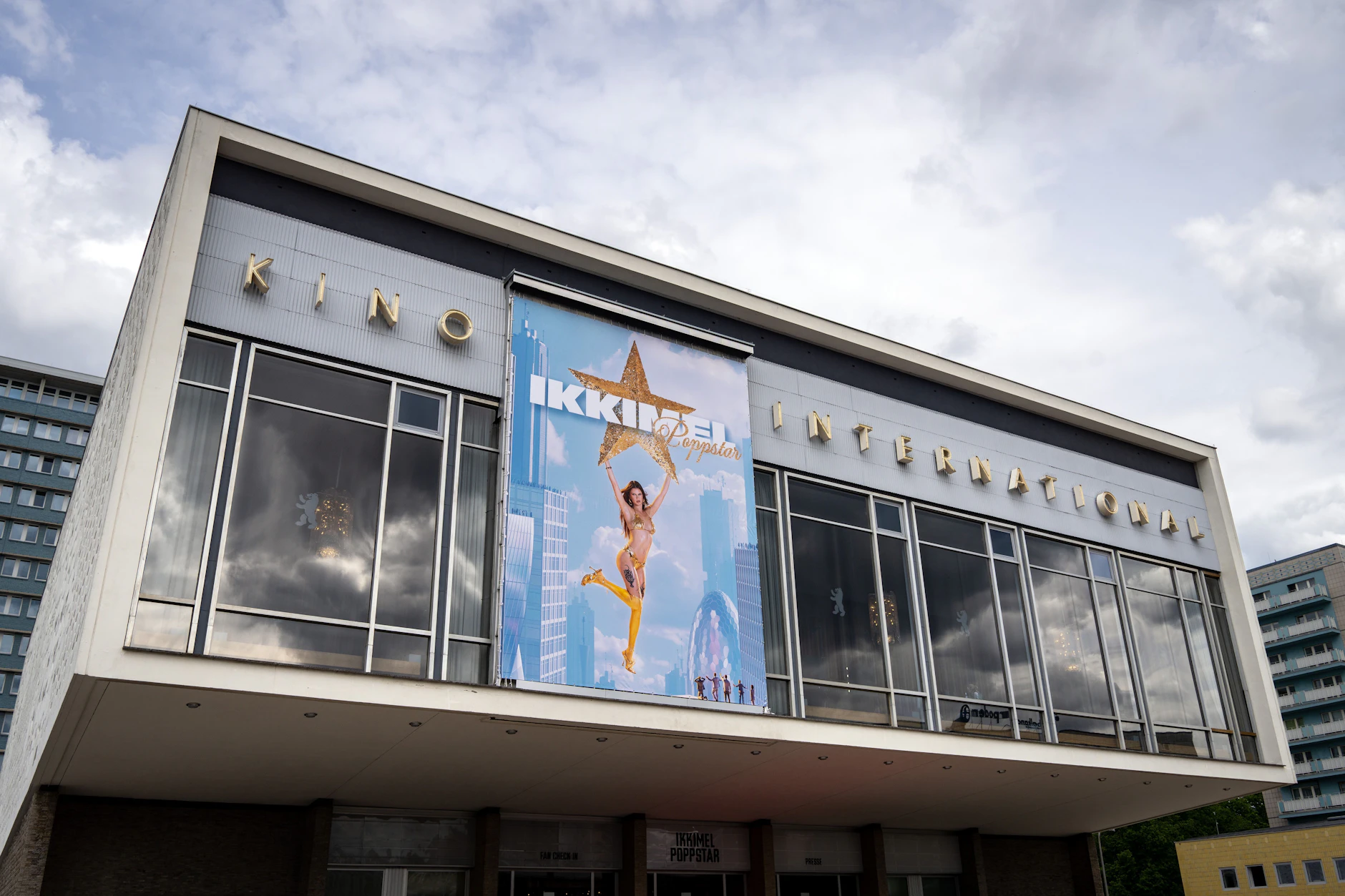 Ostmoderne gleich nebenan: Ein übergroßes Plakat mit der Aufschrift „Ikkimel Poppstar“ ist an der Fassade des Kino International angebracht.