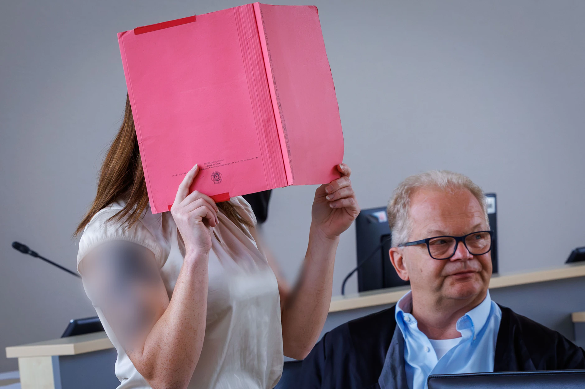 Die Angeklagte Gina H. versteckt sich hinter einem roten Hefter vor den Fotografen der Presse. Sie soll den kleinen Fabian aus Güstrow getötet haben.