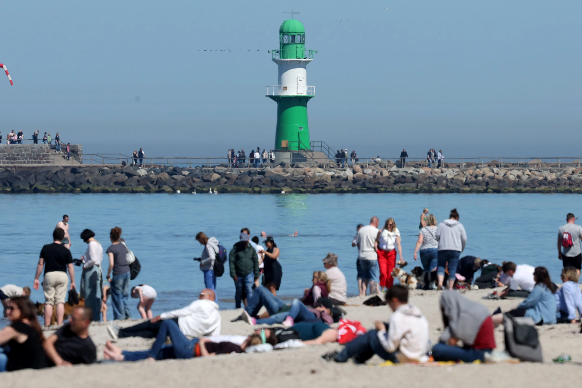 Strandbesucher genießen in Warnemünde das sonnige und warme Wetter.