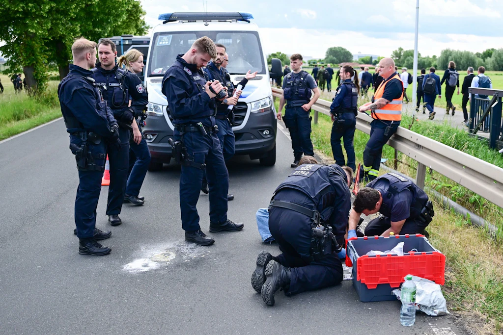 Polizeibeamte lösen während der Internationalen Luft- und Raumfahrtausstellung (ILA) auf dem Berlin ExpoCenter Airport an einer Zufahrtsstraße eine festgeklebte Person.