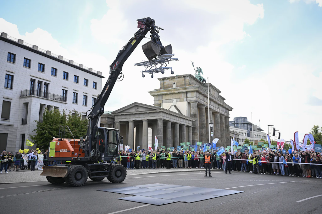 Bagger zerstört Klinikbett: Berlins Krankenhäuser demonstrieren am Brandenburger Tor gegen Kürzungen.