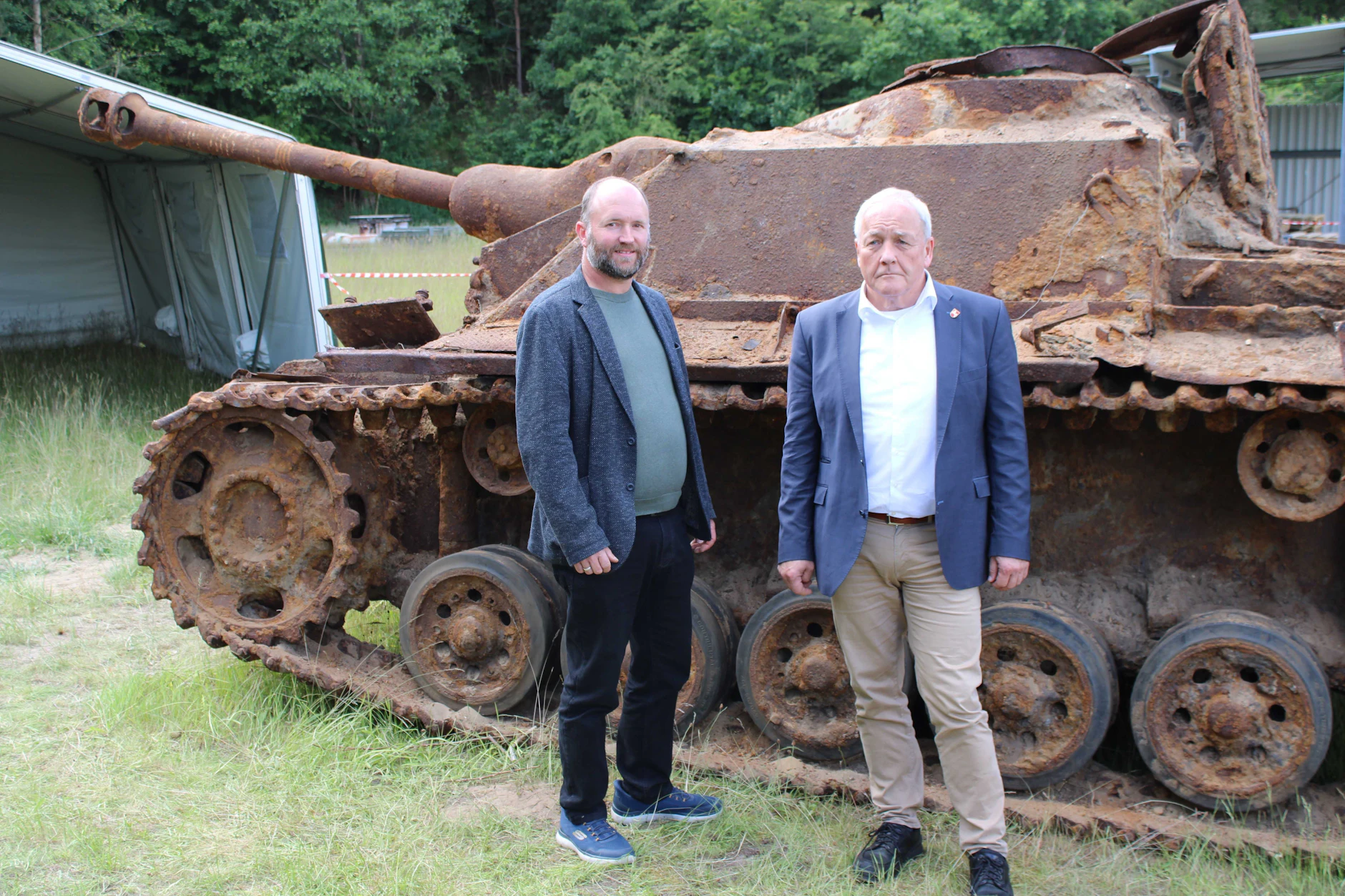 Henning Haßmann (r.), niedersächsischer Landesarchäologe, und Andreas Hüser, Leiter der Archäologischen Denkmalpflege Landkreis Cuxhaven, stehen vor einem von Rost überzogenen Sturmgeschütz III der deutschen Wehrmacht aus dem 2. Weltkrieg.