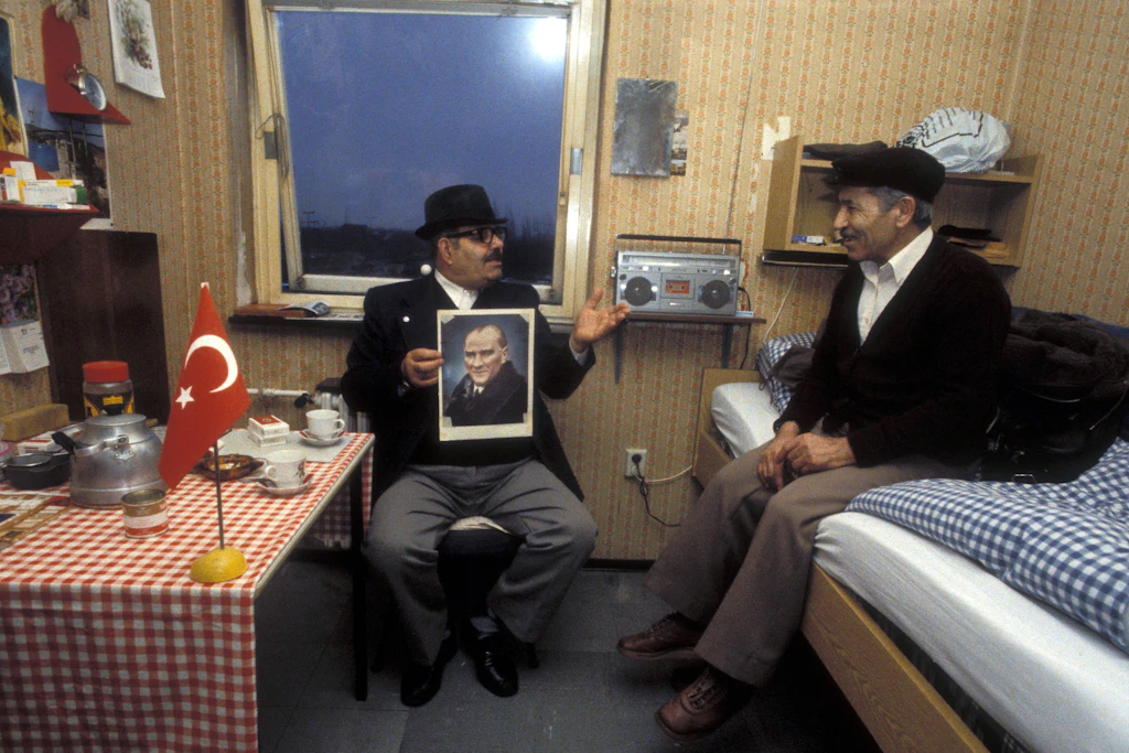 Ein türkischer Gastarbeiter hat im Jahr 1984 in Rüsselsheim einen Kollegen zu Besuch und zeigt  ein Foto von Atatürk.