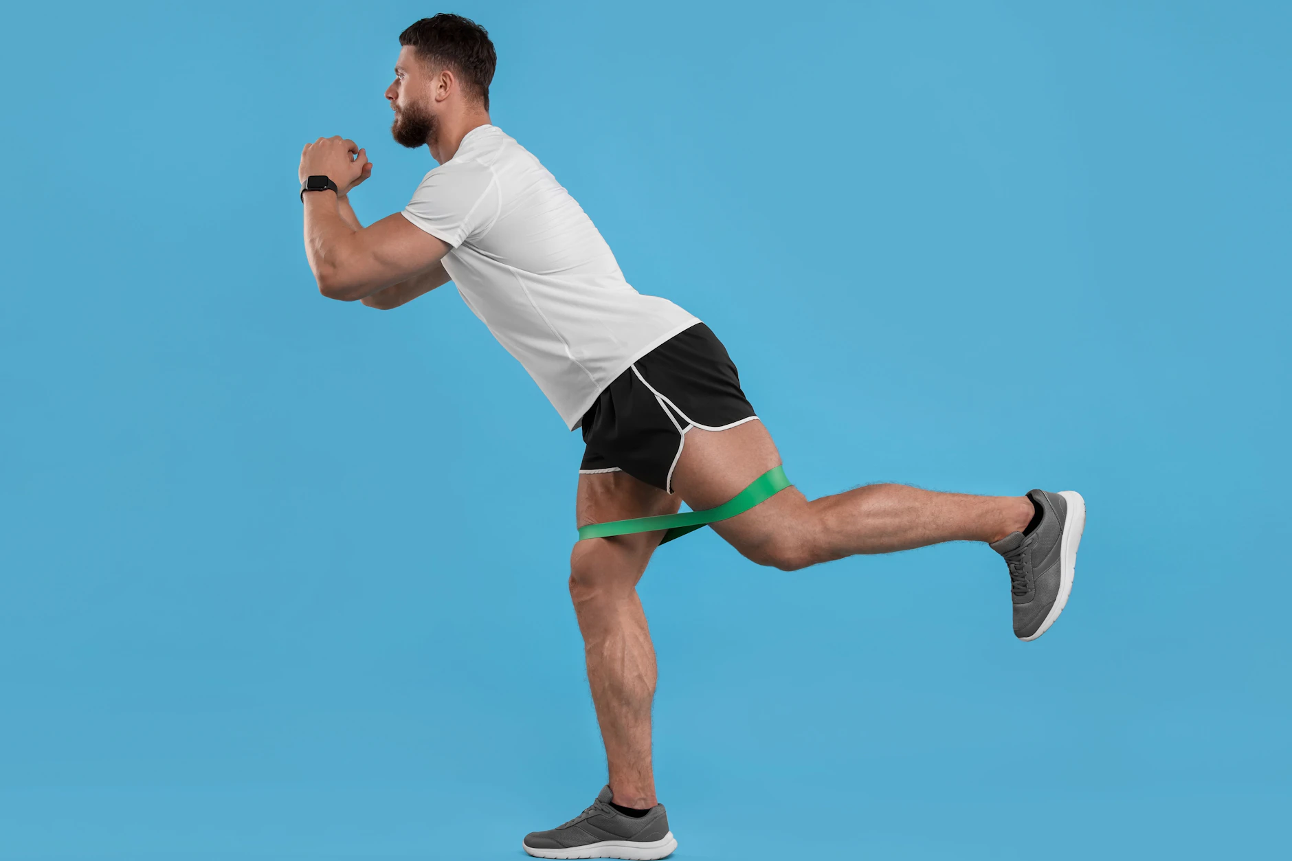 Im Stand ein Bein nach hinten strecken aktiviert den Gesäßmuskel. Mit dem elastischen Band kann man den Effekt verstärken.