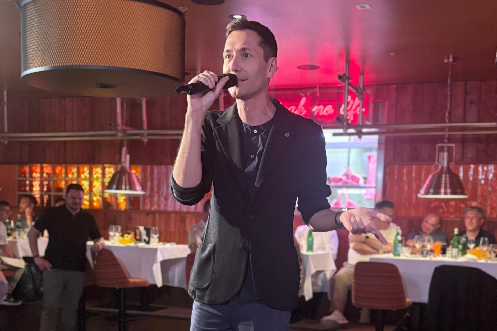 Bork Melms singt mit Mikrofon auf der kleinen Bühne im Restaurant Beast beim Pink Pride Dinner in Berlin
