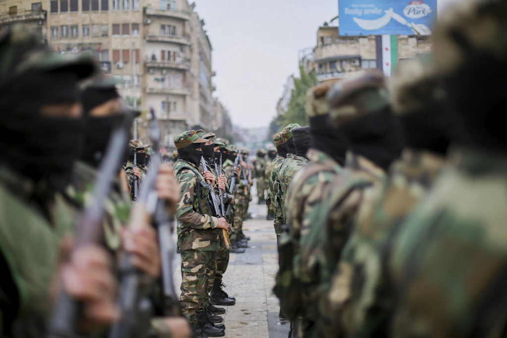 Wer ist wer? In Syrien werden Foreign Fighters, die im Bürgerkrieg teils schwerste Gewaltverbrechen an der syrischen Zivilbevölkerung verübt haben, nun zum staatlichen Schutz der Zivilbevölkerung eingesetzt.