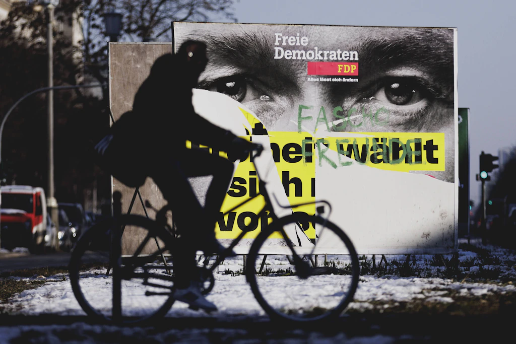 Eine Person zeichnet sich als Silhouette vor einem beschmierten Wahlplakat von der FDP mit Christian Lindner ab.
