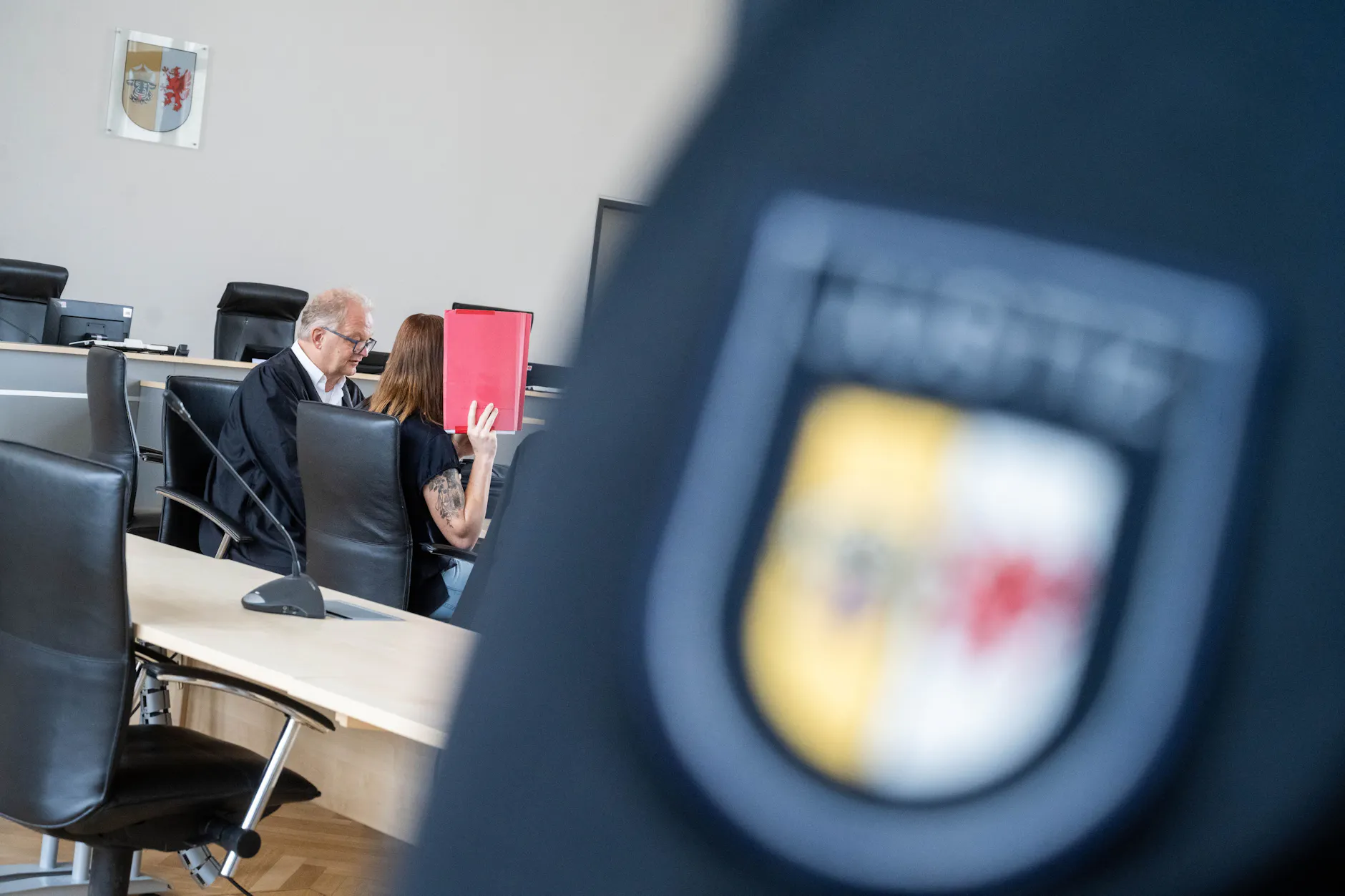 Die Angeklagte Gina H. versteckt ihr Gesicht vor Gericht hinter einem roten Hefter. Sie wird verdächtigt, den kleinen Fabian aus Güstrow getötet zu haben.