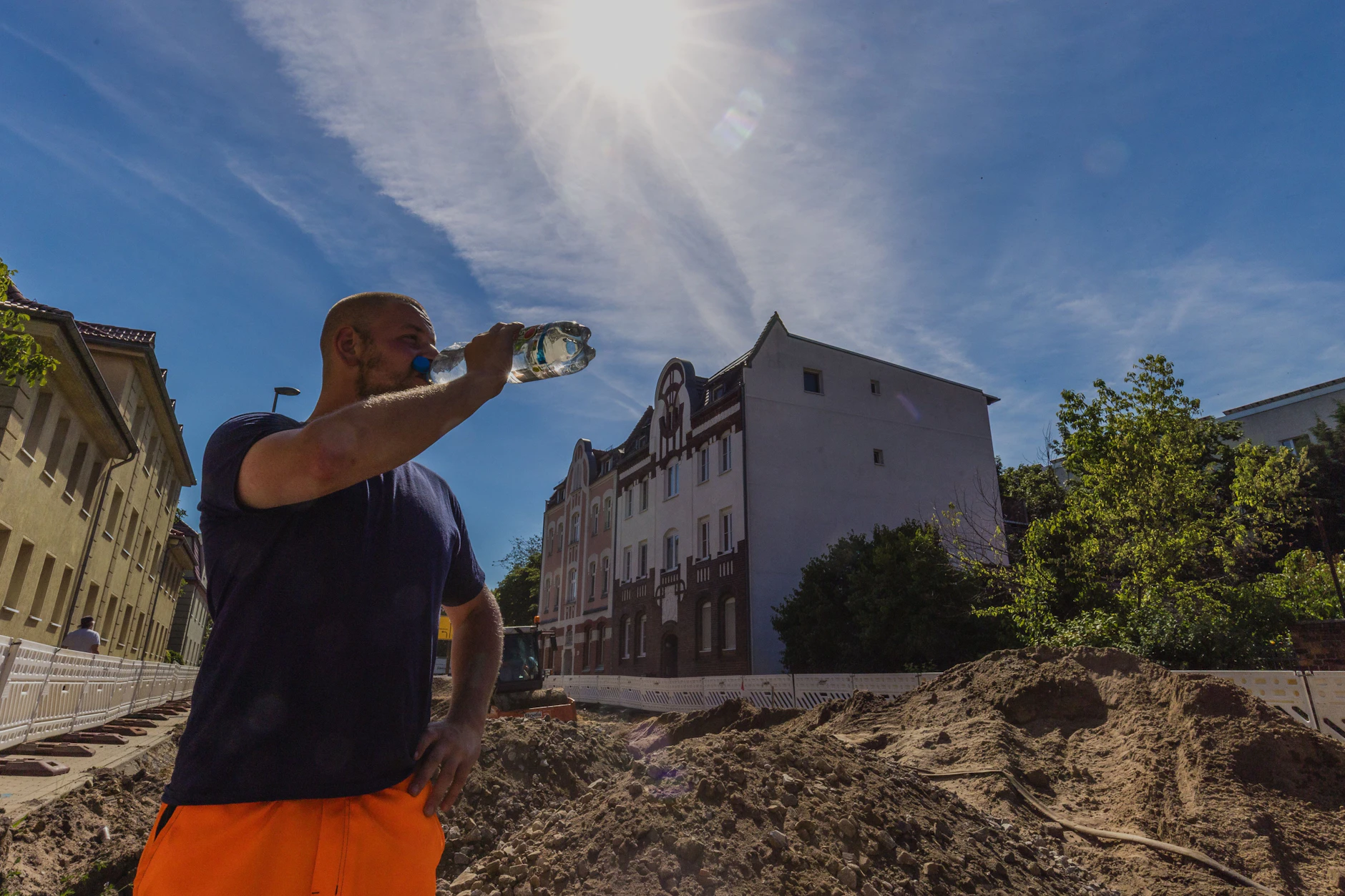 Ein Arbeiter einer Tiefbaufirma trinkt auf der Baustelle. Die Temperaturen übersteigen die 30-Grad-Marke.