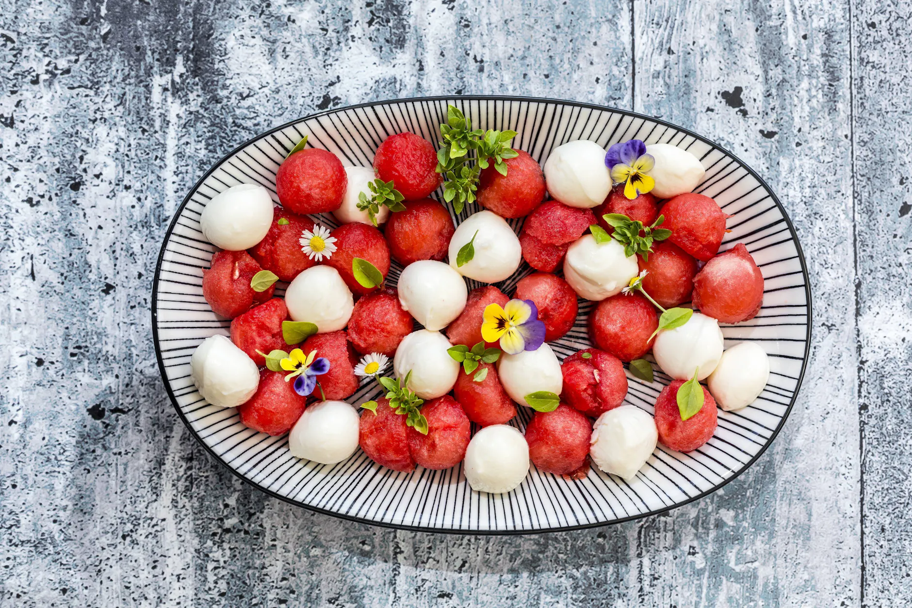 Eine optische Täuschung: Der Salat sieht aus wie die typische Vorspeise Tomate mit Mozzarella. Doch hier wird die Tomate von Melone in Kugelform ersetzt.