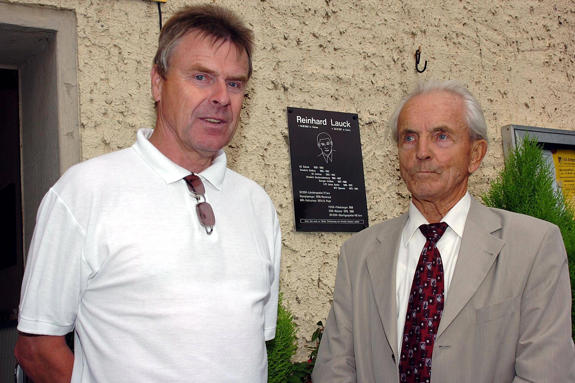 Ex-BFC-Coach Jürgen Bogs (l.) und der ehemalige DDR-Nationaltrainer Georg Buschner weihen am 16. September 2006 in Sielow die Gedenktafel (hinten) für Reinhard Lauck ein. An diesem Tag wäre „Mäcki" 60 Jahre alt geworden.