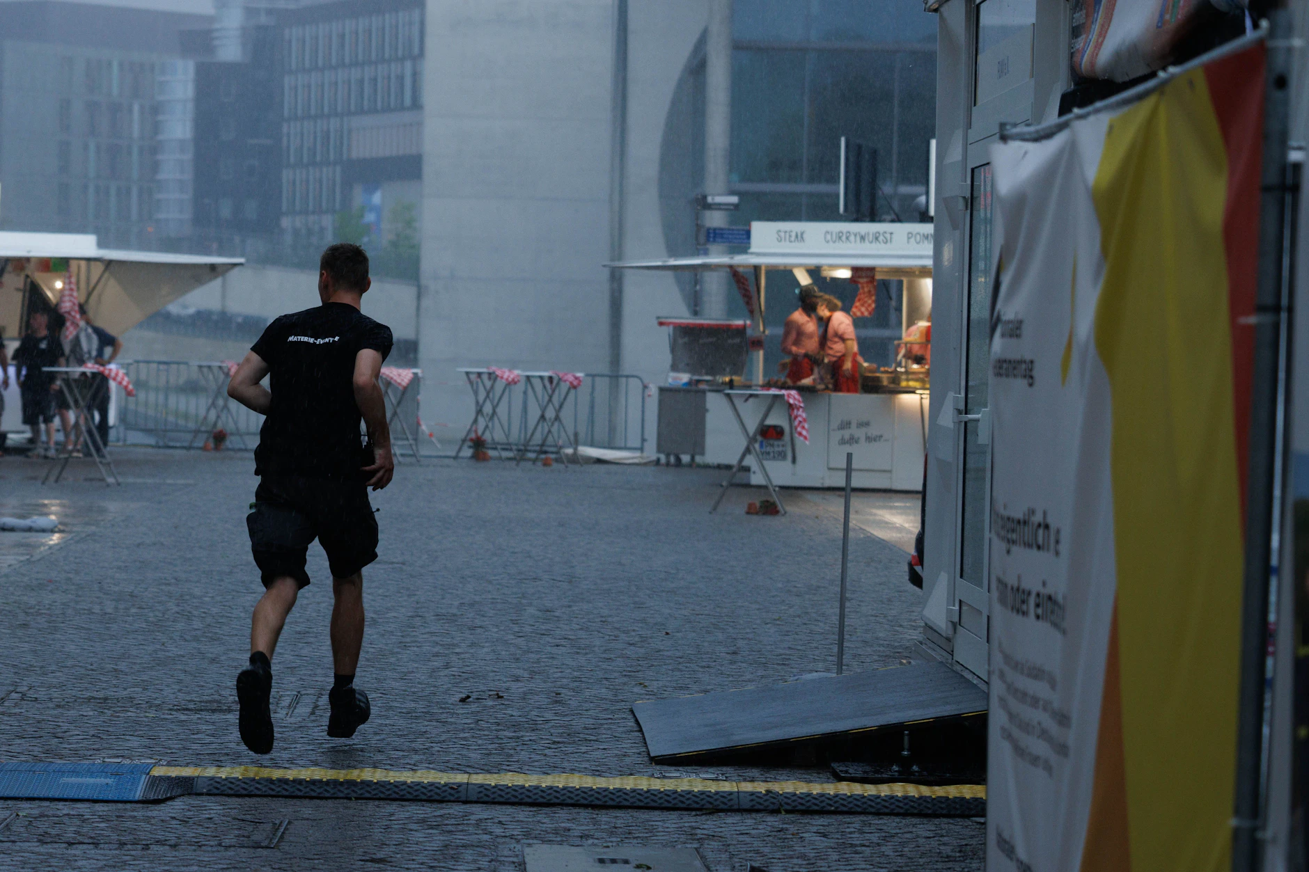 Ein Mann rennt bei heftigem Regen über das Gelände der Festveranstaltung zum Veteranentag vor dem Reichstagsgebäude.