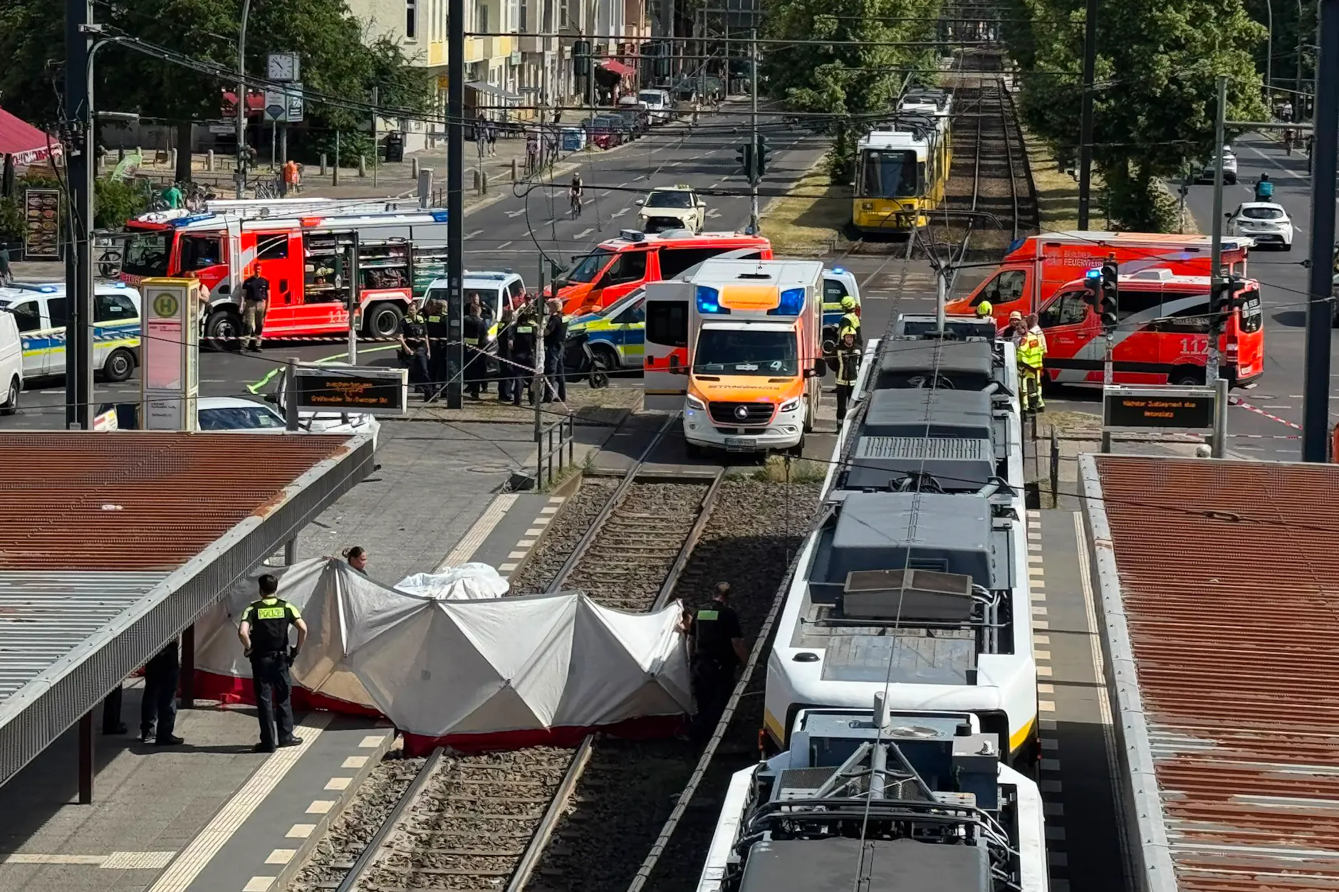 Polizisten bauen einen Sichtschutz auf. An der Kreuzung Grellstraße/Greifswalder Straße schleuderte ein PKW in eine Tramhaltestelle und verletzte einen Mann tödlich.
